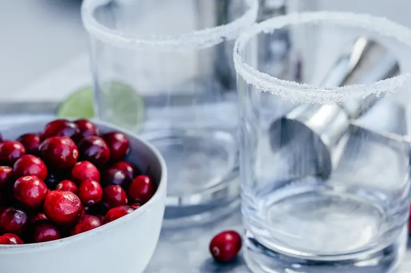 Cocktail glass with peppermint rim next to bowl of fresh cranberries