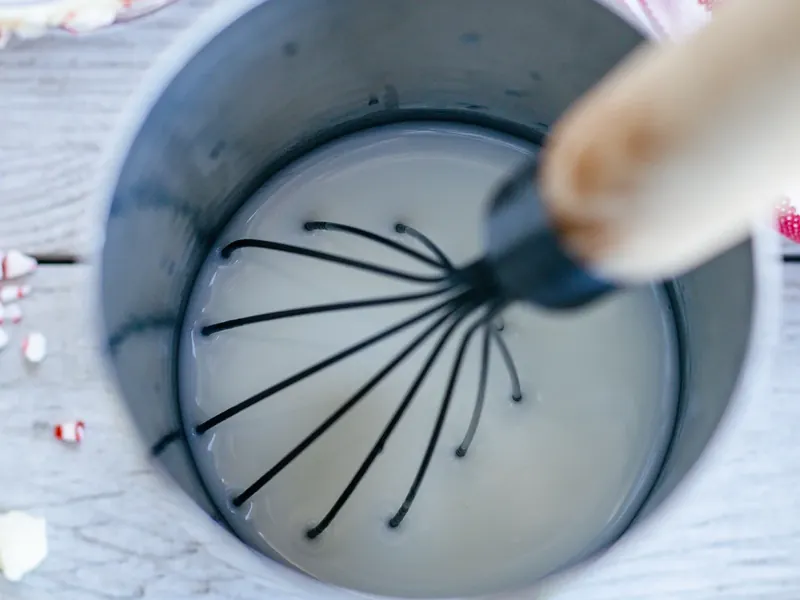 Whisking white creamy mojito mixture in a bowl with wire whisk