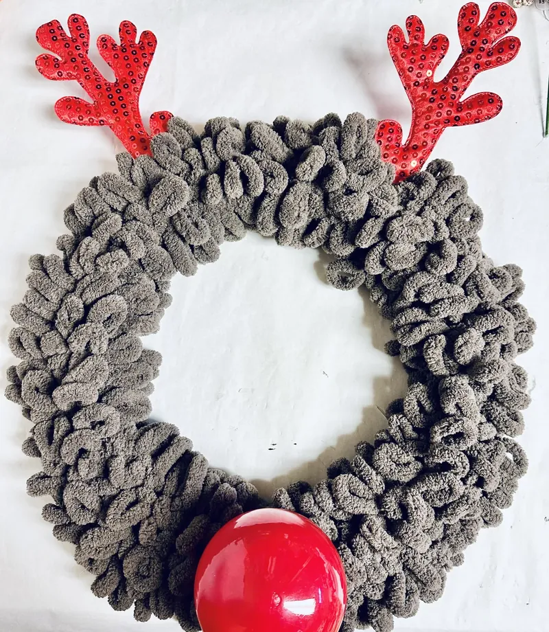 Completed yarn reindeer wreath with fluffy taupe body, red sequin antlers and red ornament nose