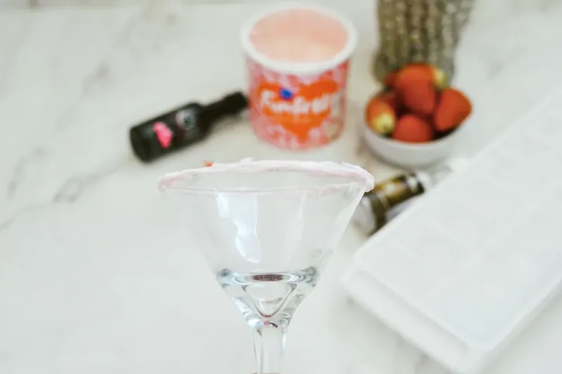Martini glass with frosted rim being prepared for Valentine's cocktail